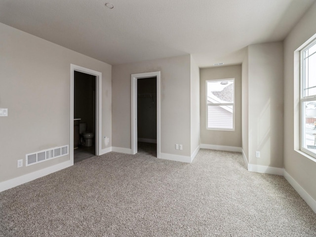 empty room featuring plenty of natural light, light carpet, and visible vents