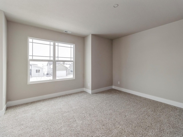 unfurnished room featuring baseboards, visible vents, and light carpet