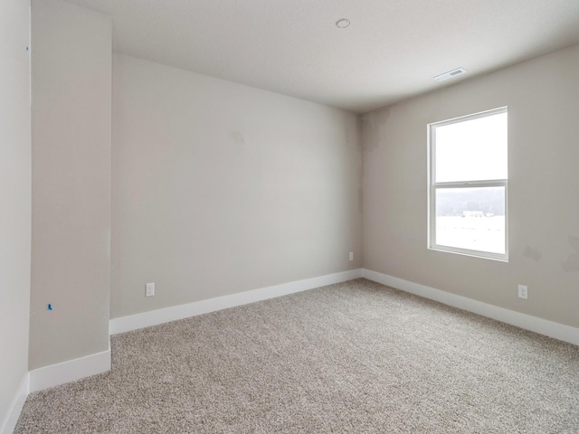 carpeted spare room featuring visible vents and baseboards