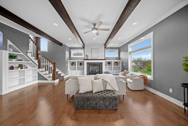 living room with a fireplace, beam ceiling, dark wood-type flooring, and ceiling fan