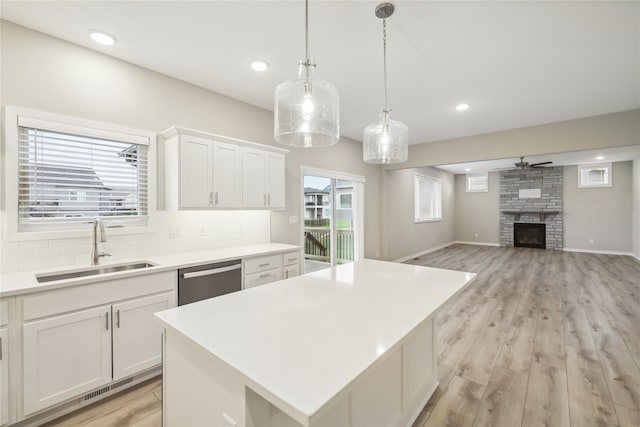 kitchen with sink, stainless steel dishwasher, a center island, and white cabinets