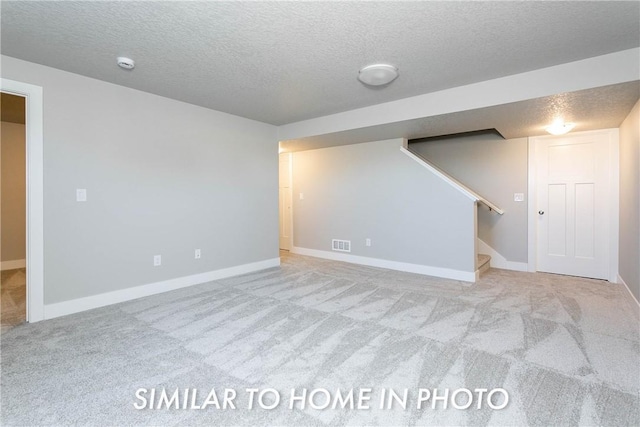 basement featuring light colored carpet and a textured ceiling