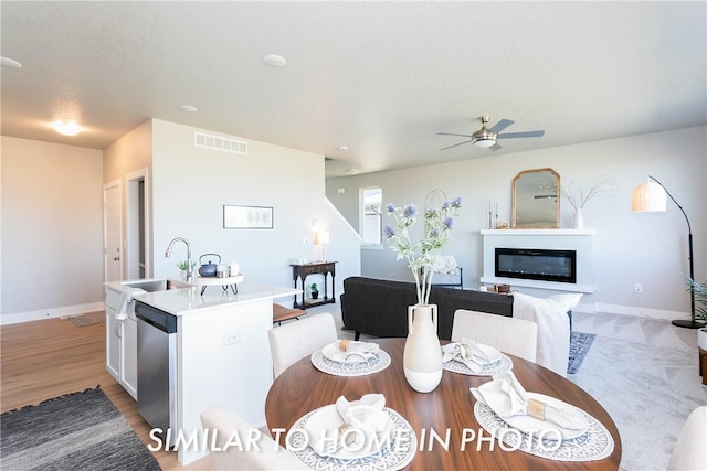 dining space with ceiling fan, light wood-type flooring, and sink