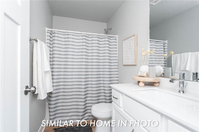 bathroom featuring a shower with curtain, vanity, toilet, and a textured ceiling