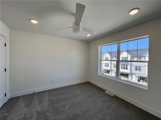 empty room featuring dark carpet and ceiling fan