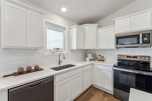 kitchen featuring sink, stainless steel appliances, backsplash, lofted ceiling, and white cabinets