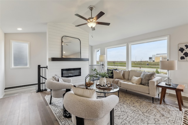 living room with a fireplace, light hardwood / wood-style flooring, ceiling fan, and lofted ceiling