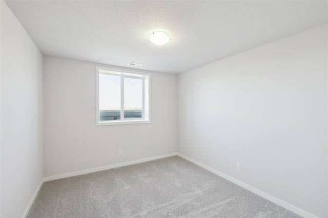 spare room featuring carpet and a textured ceiling