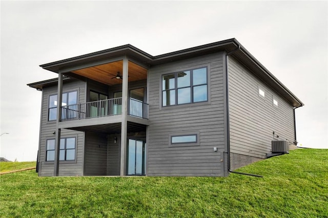 rear view of house featuring a balcony, central AC unit, ceiling fan, and a yard