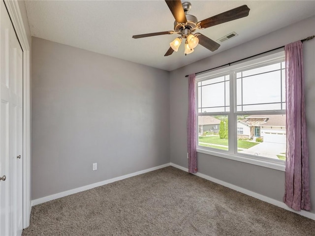 carpeted spare room featuring ceiling fan and a healthy amount of sunlight