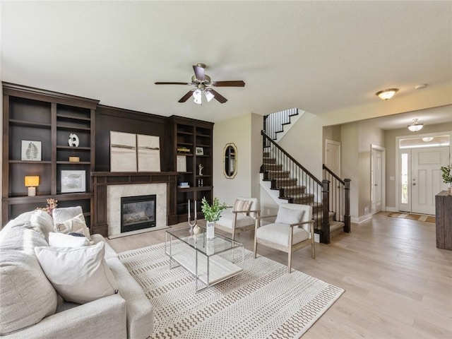 living room featuring a fireplace, light hardwood / wood-style flooring, and ceiling fan