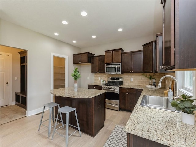 kitchen featuring sink, appliances with stainless steel finishes, tasteful backsplash, a kitchen island, and a breakfast bar area