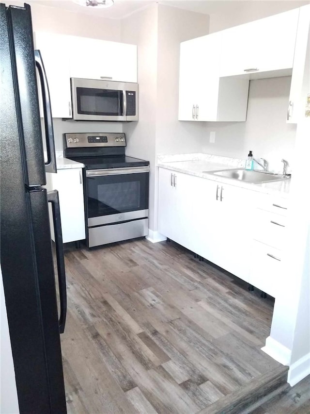 kitchen featuring stainless steel appliances, dark hardwood / wood-style flooring, white cabinets, and sink