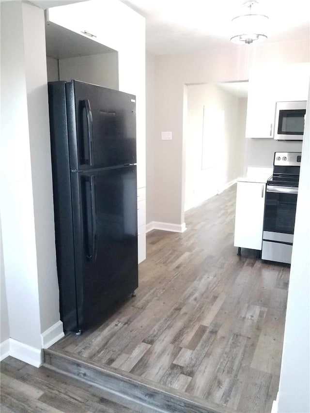 kitchen featuring dark hardwood / wood-style floors, appliances with stainless steel finishes, a chandelier, and white cabinets