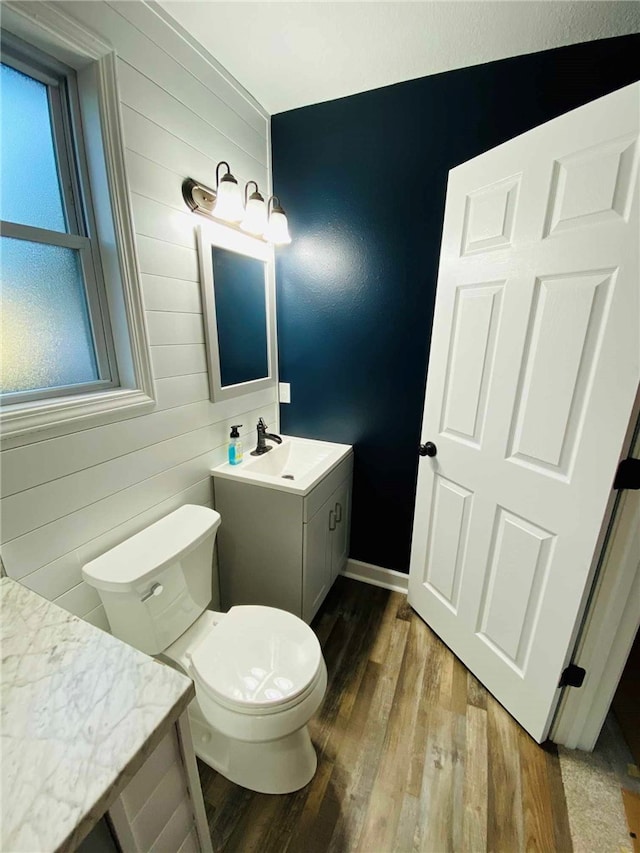 bathroom featuring wood-type flooring, toilet, vanity, and a healthy amount of sunlight