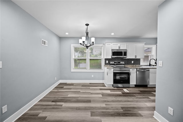 kitchen featuring tasteful backsplash, stainless steel appliances, an inviting chandelier, and white cabinets