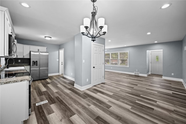 kitchen with light stone counters, hanging light fixtures, stainless steel appliances, and white cabinets