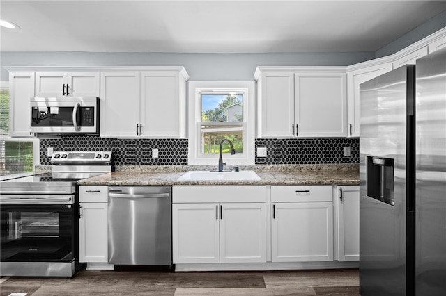 kitchen with tasteful backsplash, stainless steel appliances, sink, and white cabinets