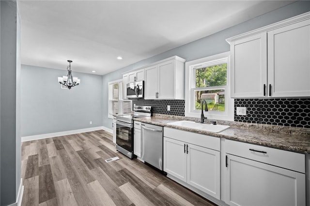 kitchen with sink, appliances with stainless steel finishes, tasteful backsplash, light hardwood / wood-style floors, and white cabinets