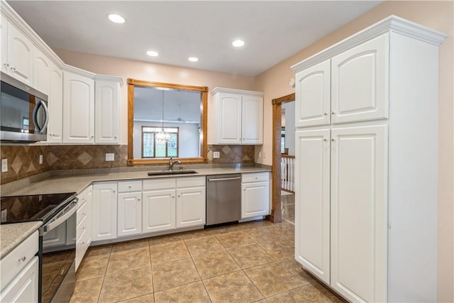 kitchen with appliances with stainless steel finishes, backsplash, white cabinetry, and sink