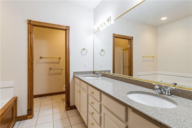 bathroom featuring a washtub, vanity, tile patterned floors, and toilet