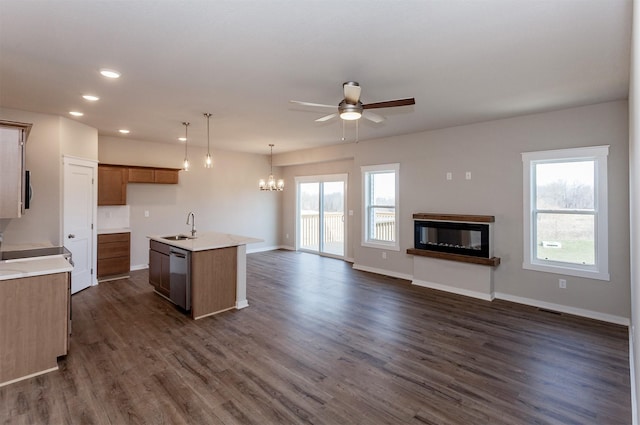 kitchen with sink, dishwasher, ceiling fan with notable chandelier, a kitchen island with sink, and dark wood-type flooring