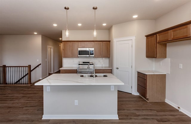7807 SE 2nd St SE, Des Moines, IA 50320 - kitchen featuring appliances with stainless steel finishes, decorative backsplash, an island with sink, brown cabinetry, and dark wood-style flooring