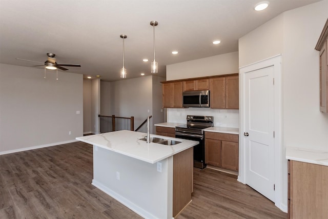 kitchen featuring a kitchen island with sink, stainless steel appliances, ceiling fan, sink, and backsplash