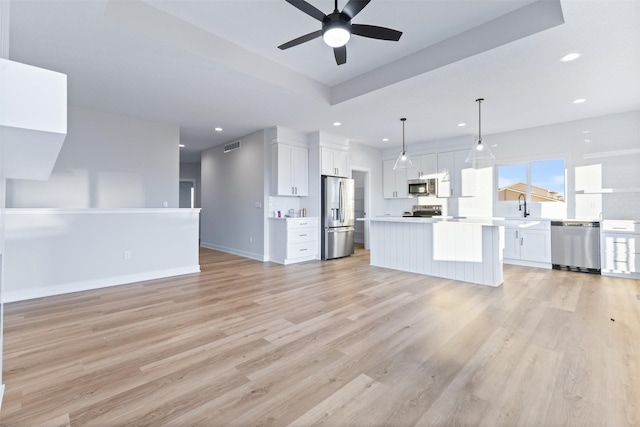 kitchen with stainless steel appliances, white cabinetry, hanging light fixtures, and a center island