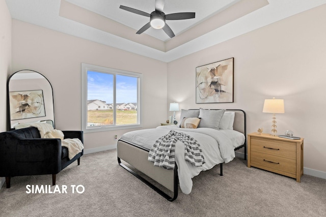 carpeted bedroom with a raised ceiling and ceiling fan