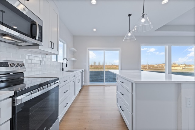 kitchen featuring appliances with stainless steel finishes, tasteful backsplash, sink, white cabinets, and a center island