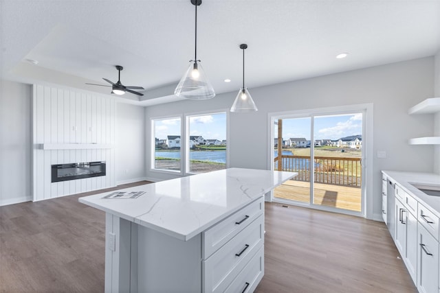 kitchen featuring decorative light fixtures, plenty of natural light, a kitchen island, a fireplace, and white cabinets