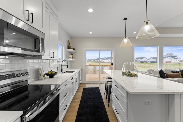 kitchen featuring white cabinetry, decorative backsplash, stainless steel appliances, and a center island