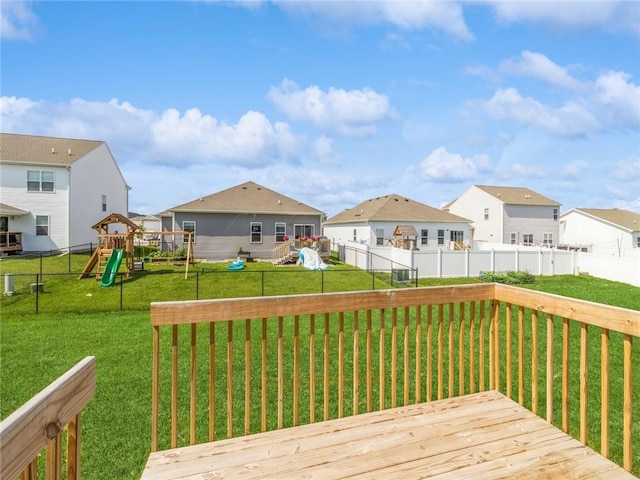 deck featuring a residential view, a lawn, a fenced backyard, and a playground