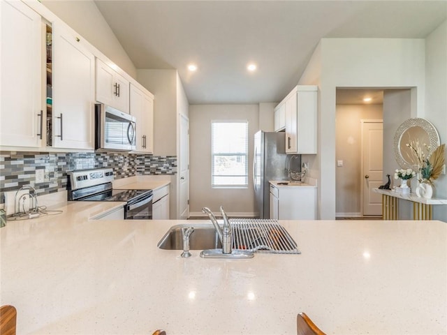 kitchen featuring backsplash, light stone countertops, stainless steel appliances, white cabinetry, and a sink