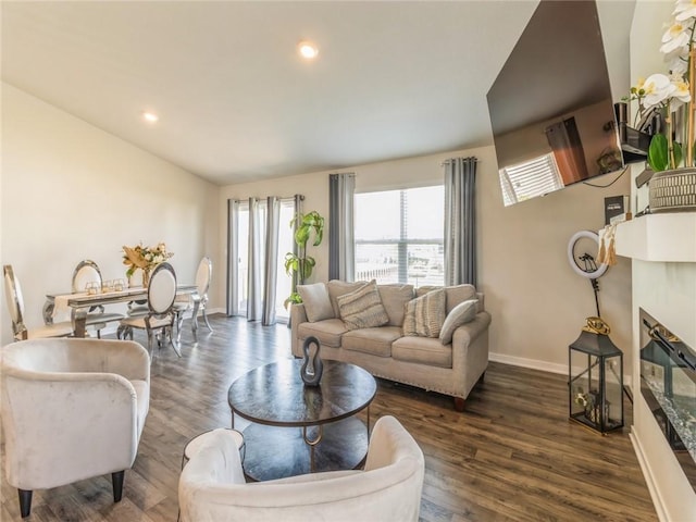 living room featuring a tiled fireplace, lofted ceiling, baseboards, and wood finished floors