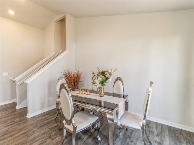 dining space with stairway, baseboards, wood finished floors, and vaulted ceiling