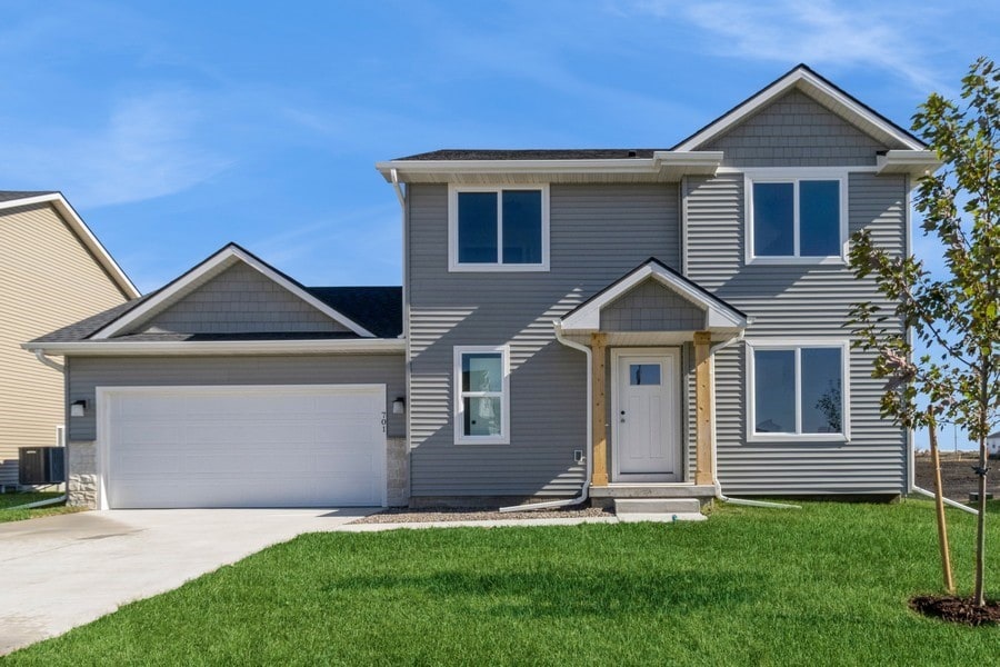 view of front facade featuring cooling unit, a garage, and a front lawn