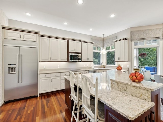 kitchen with a kitchen bar, appliances with stainless steel finishes, pendant lighting, and a healthy amount of sunlight