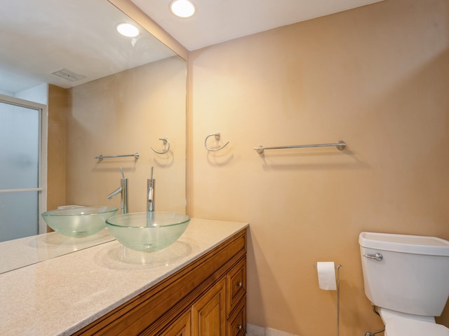 bathroom featuring vanity, toilet, and walk in shower