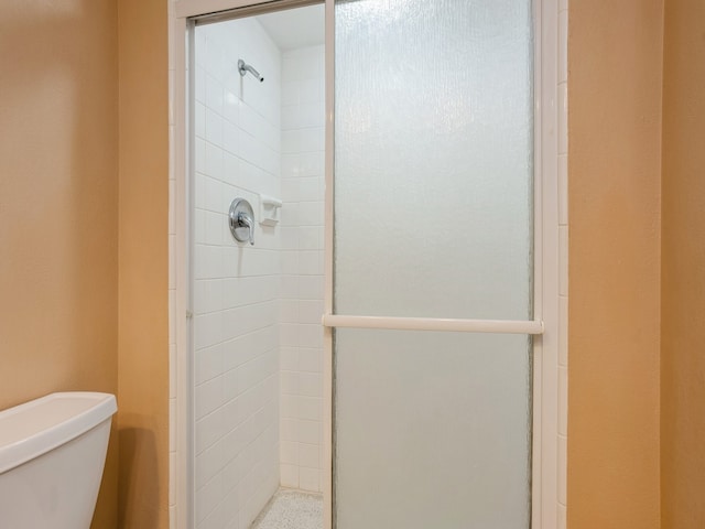 bathroom featuring a shower with shower door and toilet