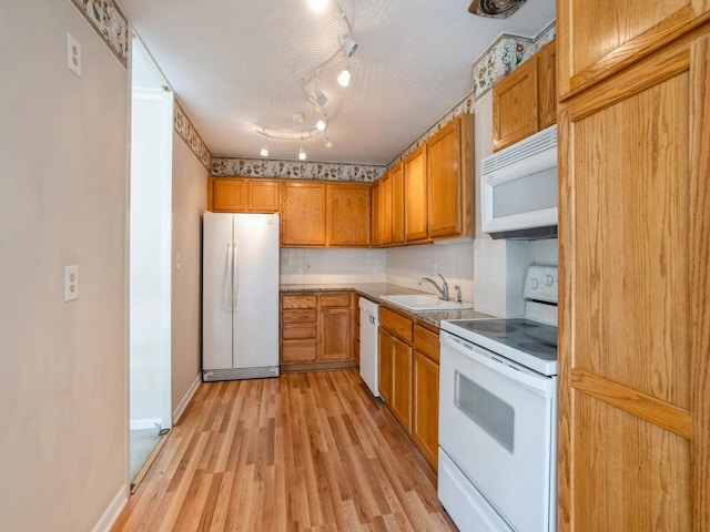 kitchen featuring white appliances, track lighting, sink, decorative backsplash, and light hardwood / wood-style floors