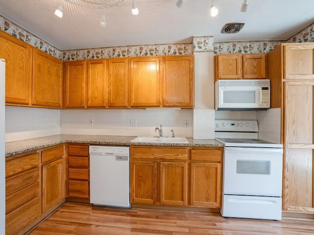 kitchen featuring white appliances, sink, light hardwood / wood-style flooring, decorative backsplash, and light stone counters