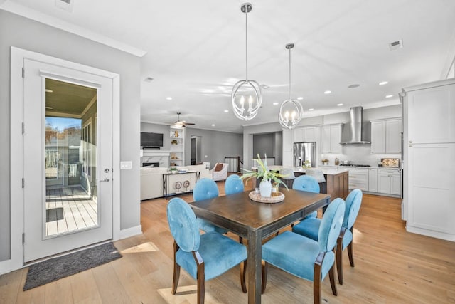 dining room with ceiling fan with notable chandelier and light hardwood / wood-style flooring