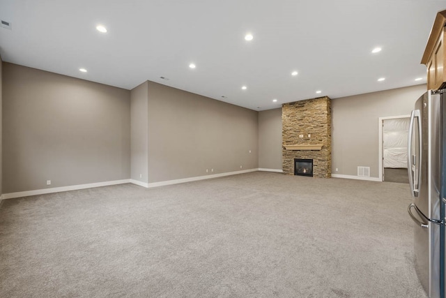 unfurnished living room featuring light carpet and a stone fireplace