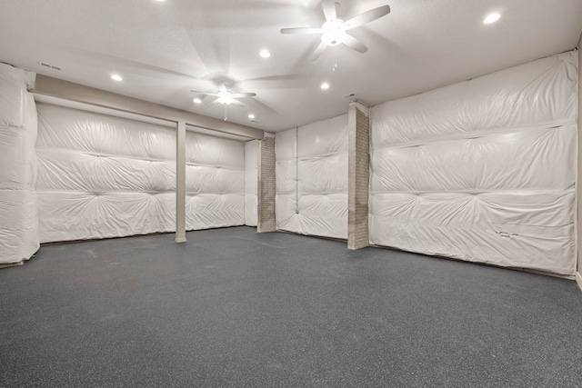 basement with a textured ceiling and ceiling fan