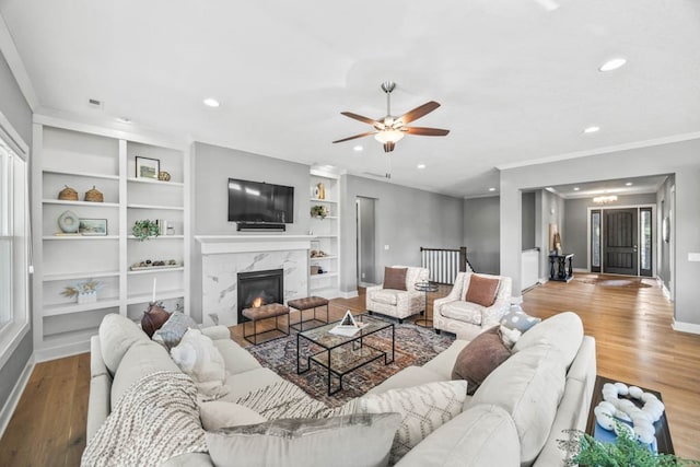 living room featuring ceiling fan, light hardwood / wood-style floors, a premium fireplace, and built in features