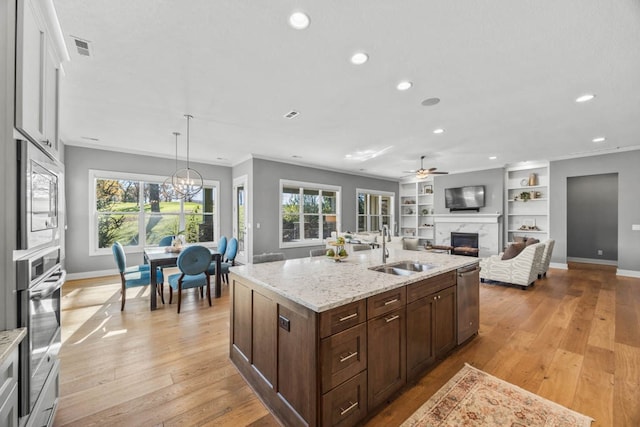 kitchen with light stone countertops, sink, light wood-type flooring, white cabinets, and appliances with stainless steel finishes