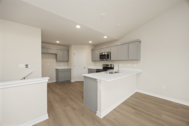 kitchen featuring gray cabinetry, sink, light wood-type flooring, kitchen peninsula, and stainless steel appliances