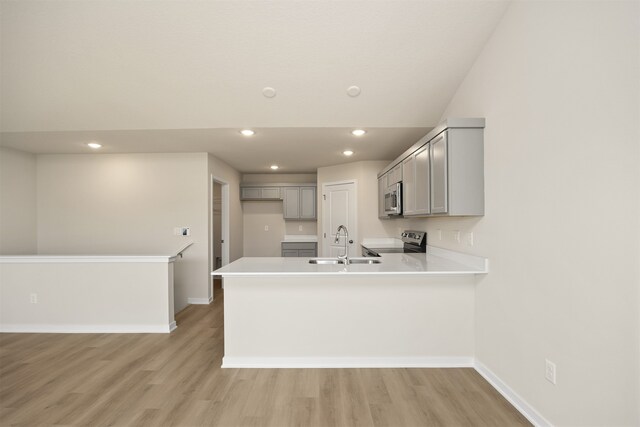 kitchen featuring gray cabinetry, kitchen peninsula, light hardwood / wood-style flooring, and appliances with stainless steel finishes